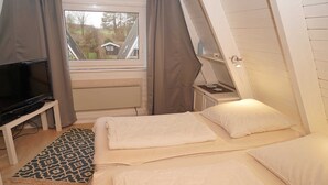 Un dormitorio con dos camas, televisión y ventana con cortinas.