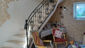 Een trap met een stenen muur, een houten balk en een tafel met stoelen en decoraties.