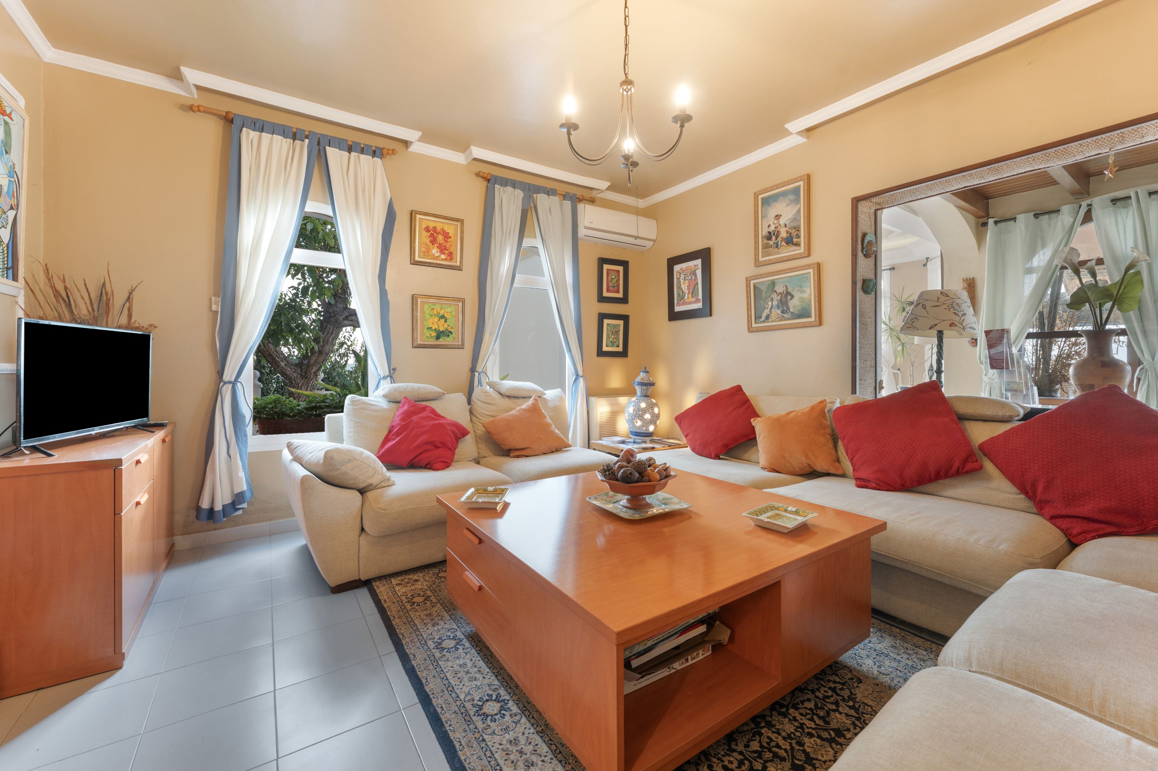 Una sala de estar con sofá, mesa de centro, televisor y obras de arte en las paredes.