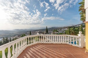 Une terrasse dotée d’une balustrade blanche, d’où l’on a vue sur la ville et les montagnes.