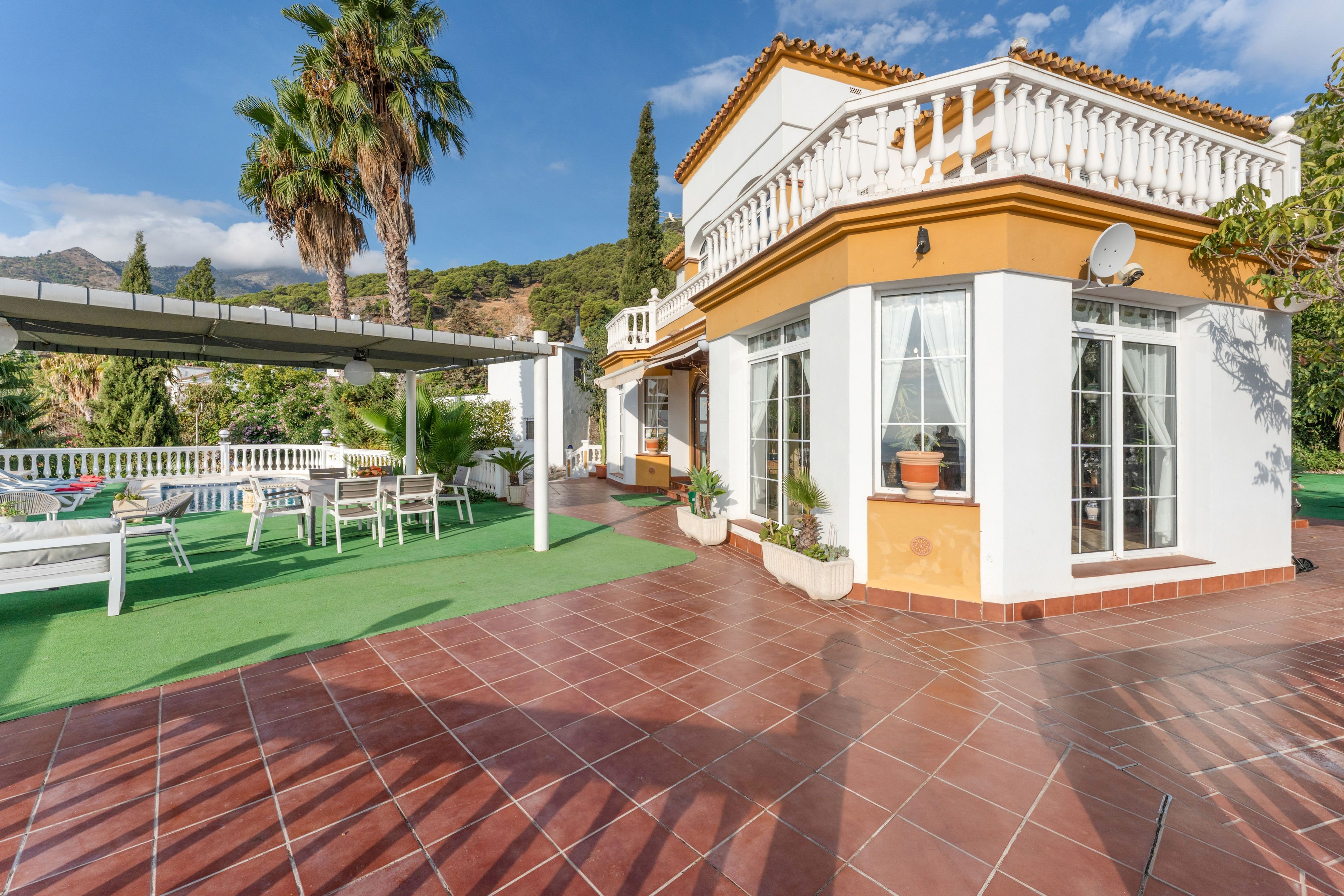 Eine Villa mit Terrasse, Sitzgelegenheiten im Freien und Bergblick.