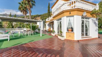 Eine Villa mit Terrasse, Sitzgelegenheiten im Freien und Bergblick.