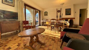 Un soggiorno con un tavolo in legno, sedie, una televisione e un camino.