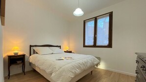 Una camera da letto con un letto, due abat-jour, una finestra e un comò.