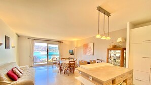 A modern living room with a sofa, a dining table, and a kitchen area with a wooden island. - 3-room apartment with terrace and parking, Veyrier-du-Lac (Veyrier-du-Lac)