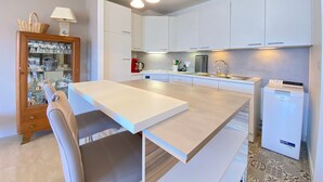 A modern kitchen with white cabinets, a central island, pendant lighting, and a small refrigerator. - 3-room apartment with terrace and parking, Veyrier-du-Lac (Veyrier-du-Lac)