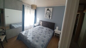 Et soveværelse med seng, et natbord, en stol, en hængende lampe og et billedværk på væggen.