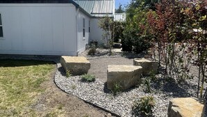 A residential area with a white house, a gravel pathway, and a small garden with rocks and plants. - CUTE COTTAGE WITH A GAME ROOM (Belgrade)