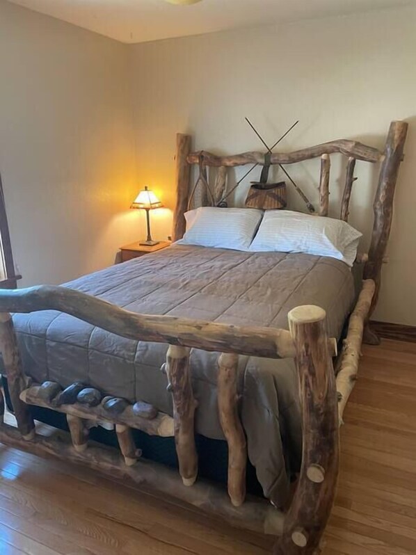 Ein Bett mit einem rustikalen Holz-Kopfstück und einer schlichten Nachttischlampe.