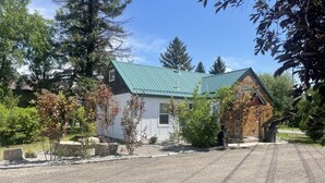 A small, single-story building with a green metal roof, surrounded by trees and gravel driveway. - CUTE COTTAGE WITH A GAME ROOM (Belgrade)