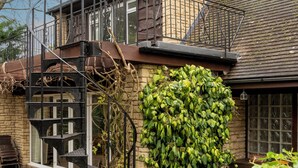 Una casa con facciata in pietra, una scala in legno e un'ampia parete ricoperta di edera verde.