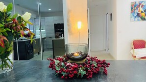 Una cocina moderna con comedor, que presenta un candelabro de vidrio rodeado de bayas rojas y un jarrón con rosas blancas.