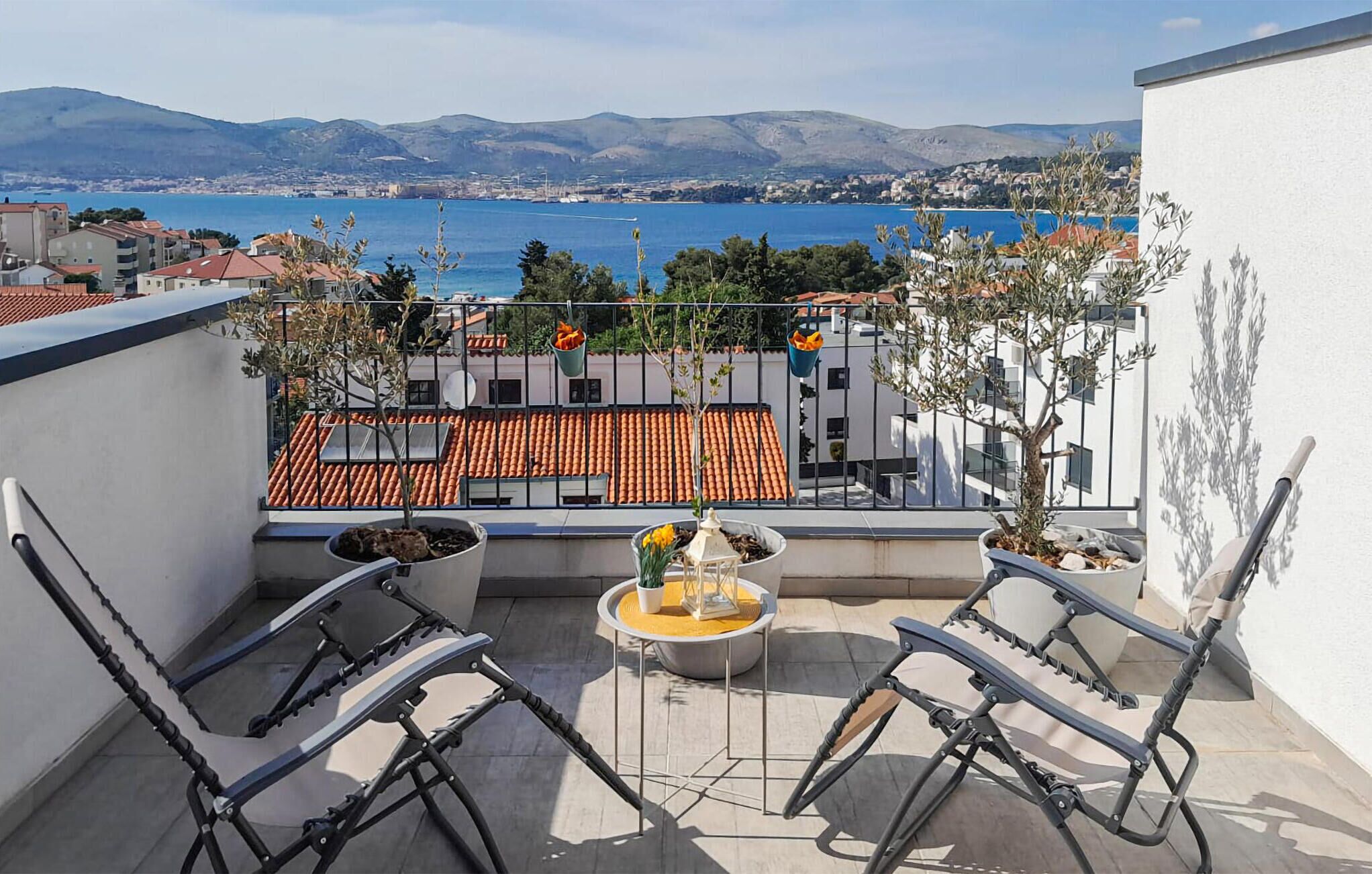 A balcony with two chairs, a small table, and potted plants.