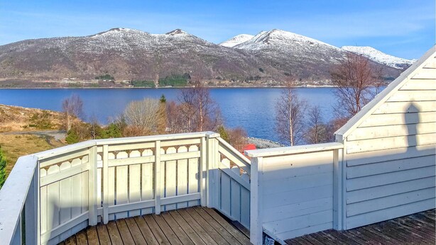A deck with a view of a lake and snow-capped mountains.