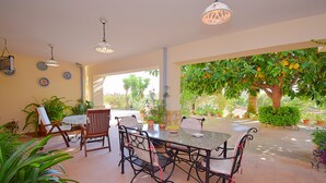 An outdoor patio with a table and chairs, surrounded by potted plants and a view of a garden. - Can Nina 198 traditional finca with private swimming pool, terrace, barbecue and WiFi (Campanet)