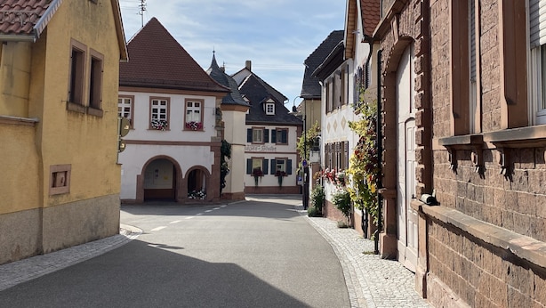 Eine enge Straße, gesäumt von traditionellen europäischen Gebäuden, mit einem Restaurant und einer Apotheke.