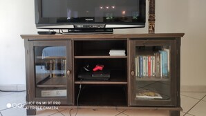 A television on a wooden stand with a glass cabinet below. - Guest house ideally located (La Teste-de-Buch)