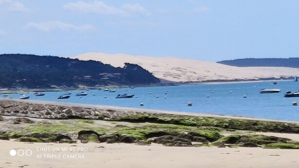 A beach with boats, rocky shore, and hills in the background. - Guest house ideally located (La Teste-de-Buch)