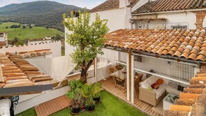 Une cour avec un arbre, un canapé en osier et une table à manger.