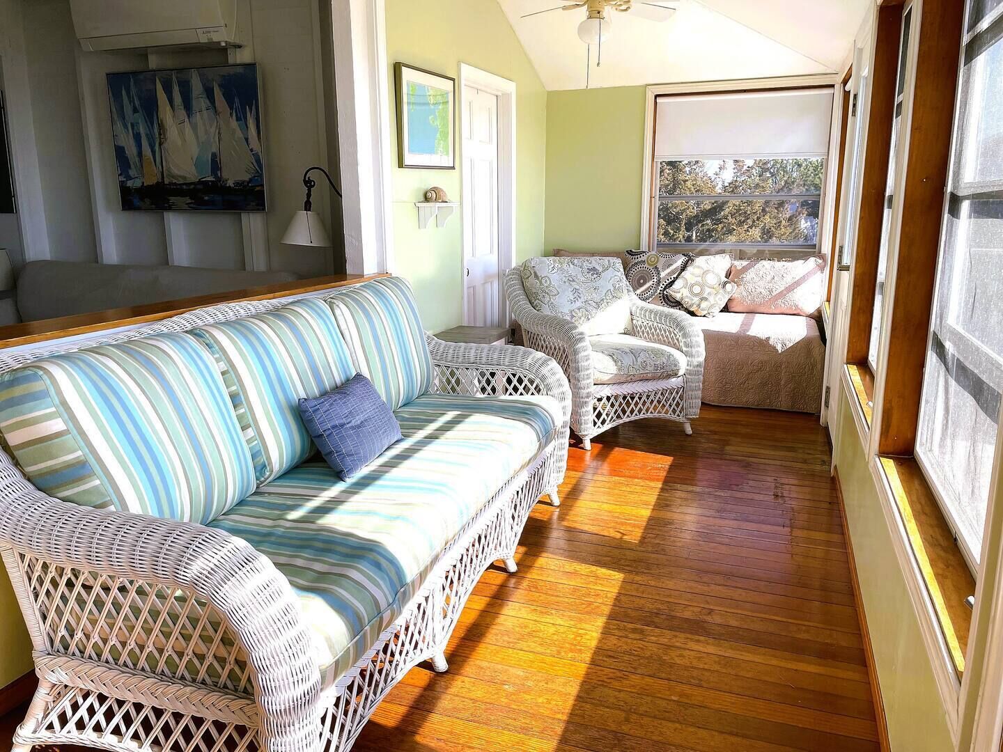 Una habitación acogedora con un sofá a rayas, sillas de mimbre y suelo de madera.
