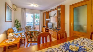 A room with a dining table, chairs, a television, and a cabinet with glass doors. - Cozy apartment in Alicante (Alacant) with sauna (Alicante (Alacant))