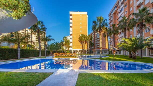 A swimming pool with a clear view of a tall building in the background. - Cozy apartment in Alicante (Alacant) with sauna (Alicante (Alacant))