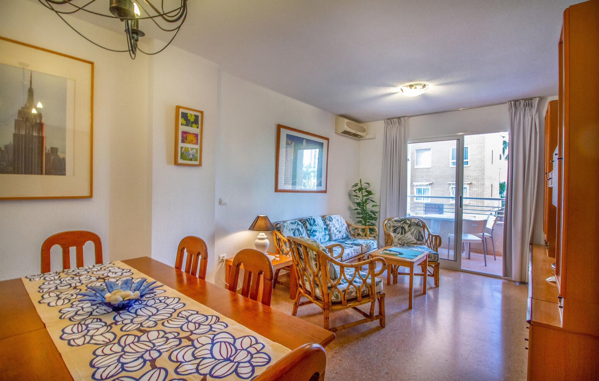 Ein Wohnzimmer mit Esstisch, Stühlen, einer Couch und einem Balkon mit Blick auf Gebäude.