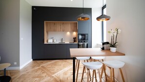 Eine moderne Küche mit dunklen Schränken, Holzdetails und einer zentralen Kochinsel mit Barhocker.