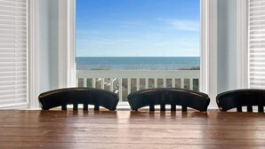 Une pièce avec un plancher en bois, une fenêtre avec des volets blancs et trois chaises noires placées face à la fenêtre.