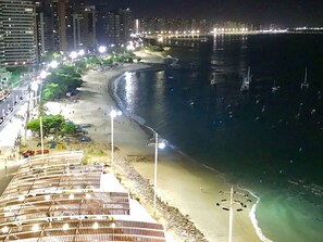 Vista de la playa con un paseo marítimo, arena y océano.