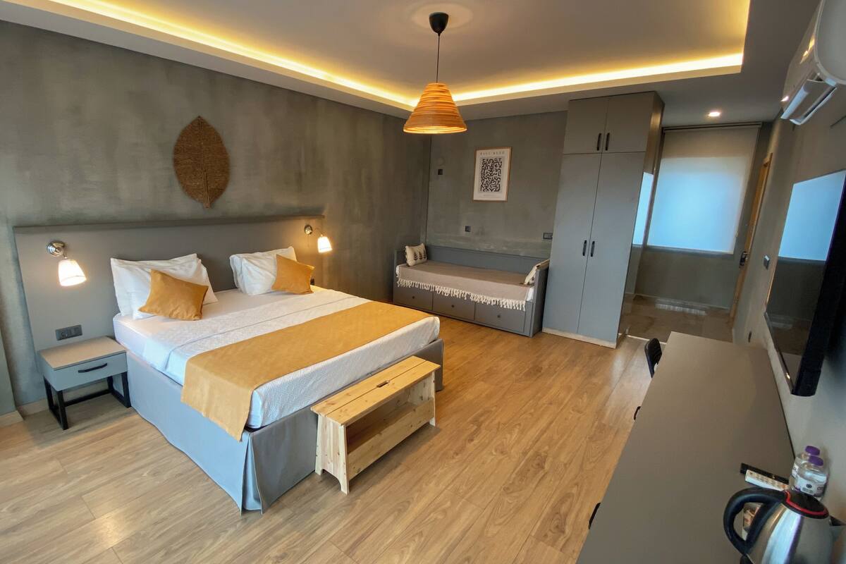 A modern bedroom with a bed, bedside tables, a bench, a wardrobe, and a television.