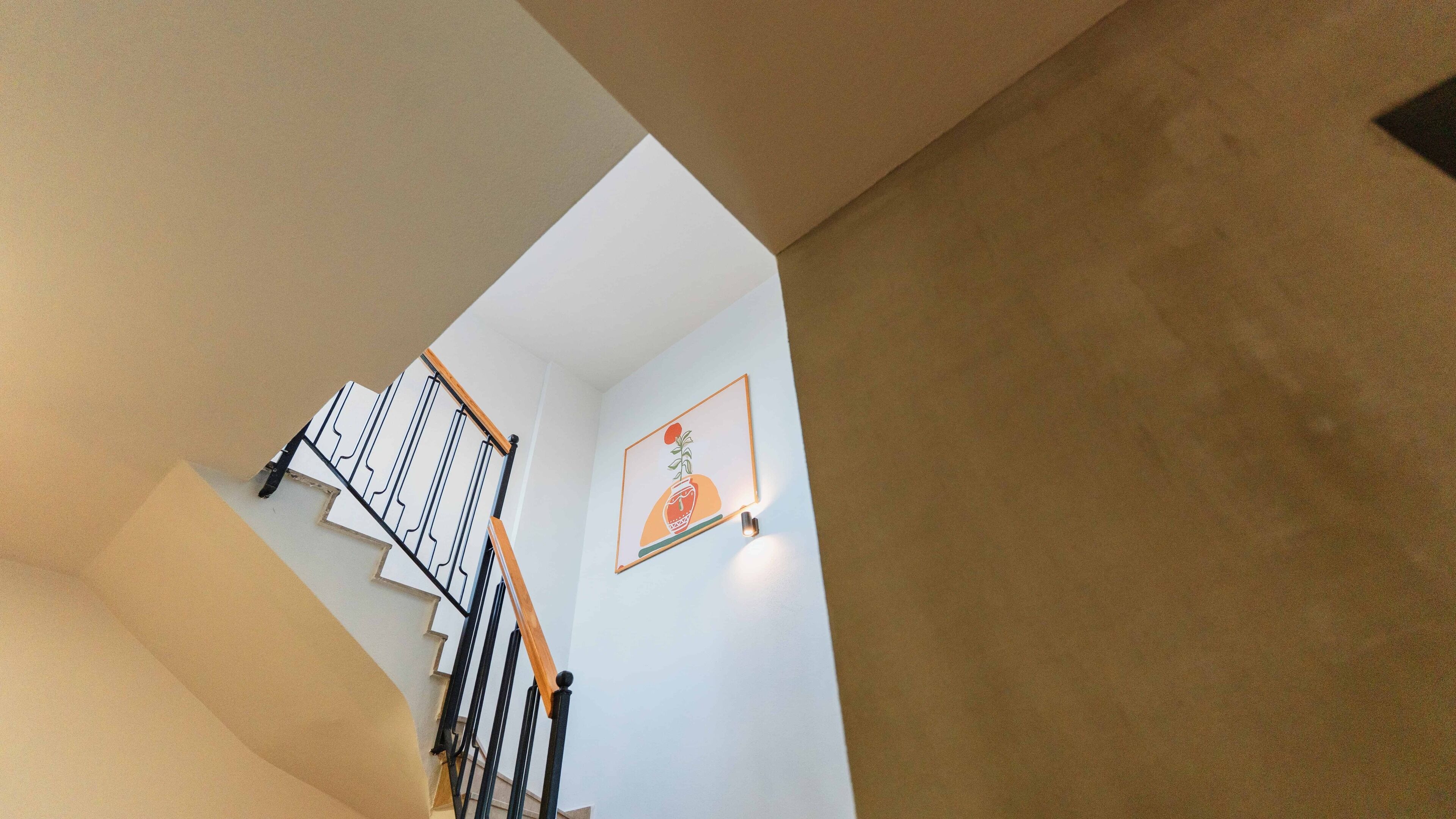 A staircase with a white wall and a framed picture of a plant.