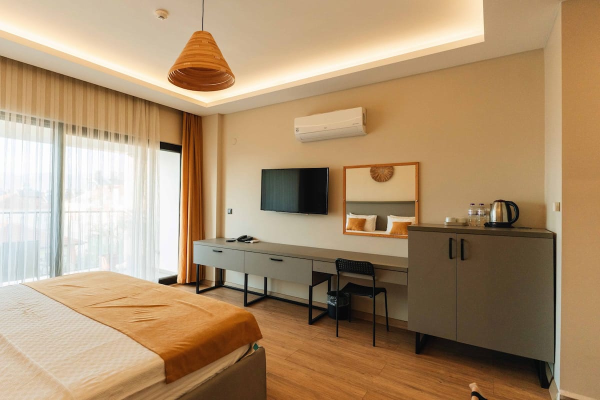 A modern hotel room with a bed, desk, chair, and a television.