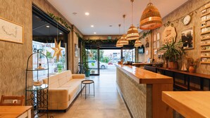 Un interior moderno con una mesa de recepción, un área de descanso y elementos decorativos como plantas y obras de arte.