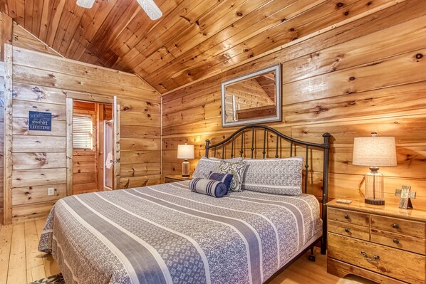 A wooden cabin bedroom with a bed, nightstands, and a mirror. - Morning Glory is the place for you! Nestled on Bluff Mountain, just 10 minutes outside of Pigeon Fo (Sevierville)