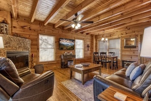 A cozy cabin interior with a fireplace, leather seating, a dining area, and wooden walls. - Morning Glory is the place for you! Nestled on Bluff Mountain, just 10 minutes outside of Pigeon Fo (Sevierville)