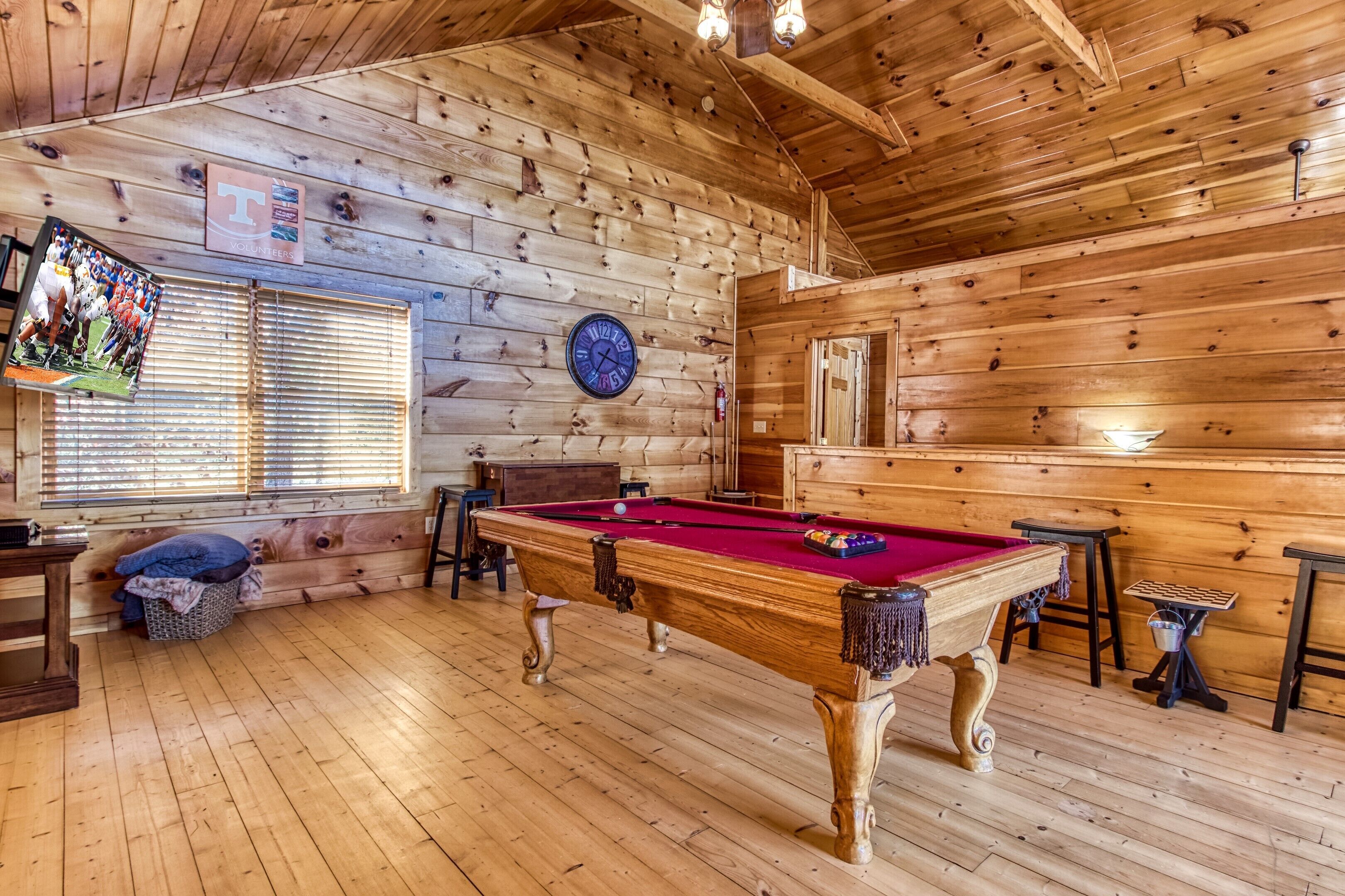 Une pièce aux murs lambrés, équipée d’une table de billard, d’un porte-billes et d’un porte-queues.