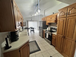 A kitchen with wooden cabinets, a refrigerator, stove, and a dining area with a table and chairs.
