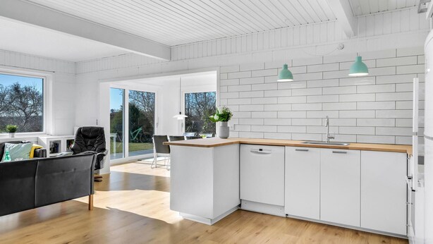 A modern kitchen with white cabinets, a wooden countertop, and a large window. - 4 bedroom awesome home in Dronningmølle (Dronningmølle)