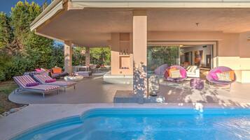 Relax by the pool surrounded by a covered patio with lounge chairs and dining area.