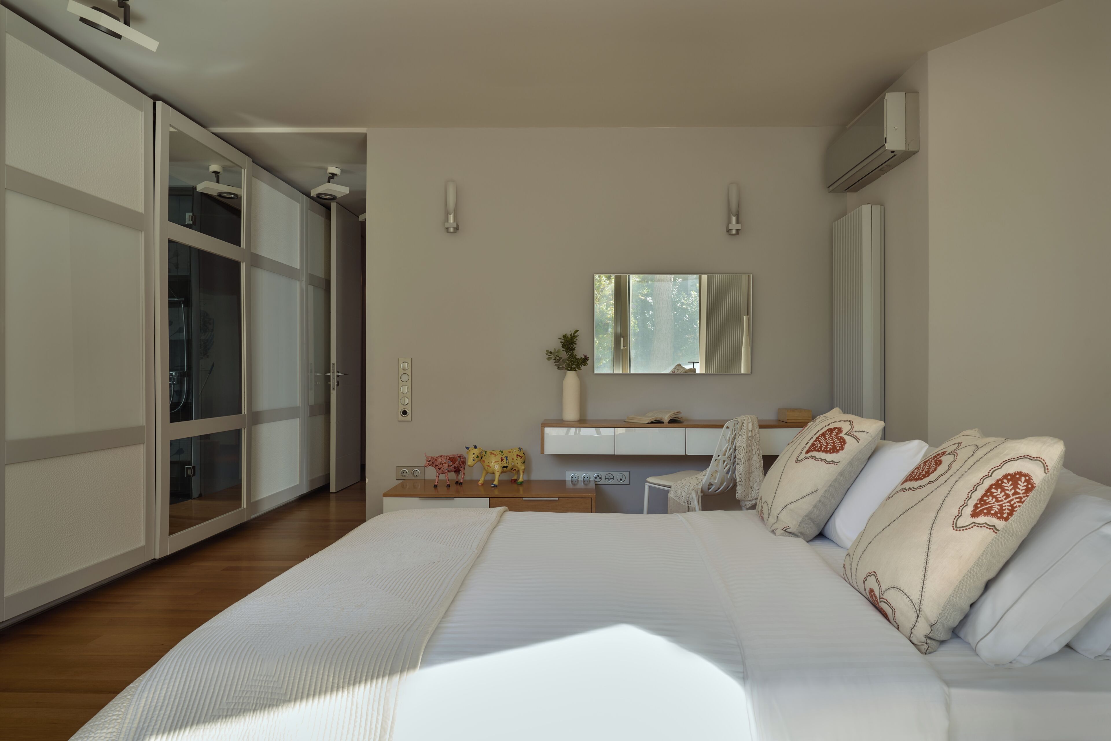 Un dormitorio con cama, escritorio, silla, armario y espejo.