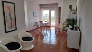 A spacious living area with a dining table, chairs, a sofa, and a TV stand. - Carcavelos Surf Beach House (Carcavelos)