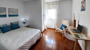 A bedroom with a bed, a desk with a laptop, a chair, and a window with curtains. - Carcavelos Surf Beach House (Carcavelos)