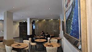 A modern hotel lobby with a reception desk, seating area, and a large painting on the wall. - Acar Airport Hotel Plus (Arnavutköy)