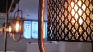 A close-up of a metal lamp with a diamond-patterned shade, a copper-colored pole, and blurred background lights. - Acar Airport Hotel Plus (Arnavutköy)