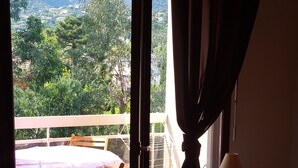 Een open schuifdeur die leidt naar een balkon met een tafel, stoelen, een lamp en een bed in een kamer.
