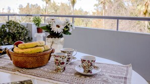 Une table sur laquelle se trouve un panier tressé contenant des bananes, une carafe, ainsi que des tasses et des soucoupes décorées de motifs floraux.