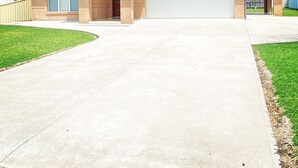 Una casa de un piso con garaje, un porche cubierto y un césped cuidado.