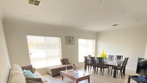 Amplia sala de estar con sofá, una mesa de centro y comedor con sillas y una mesa.