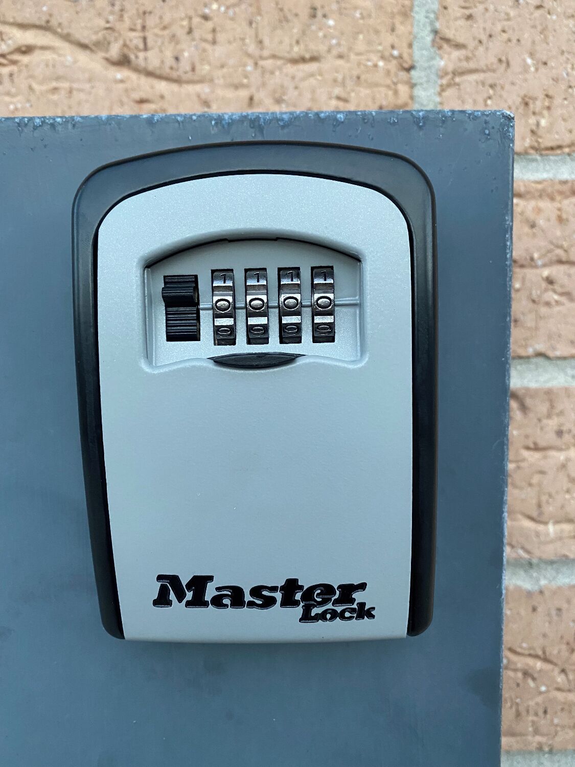 Un cadenas à combinaison de la marque Master Lock, fixé sur une surface métallique grise.